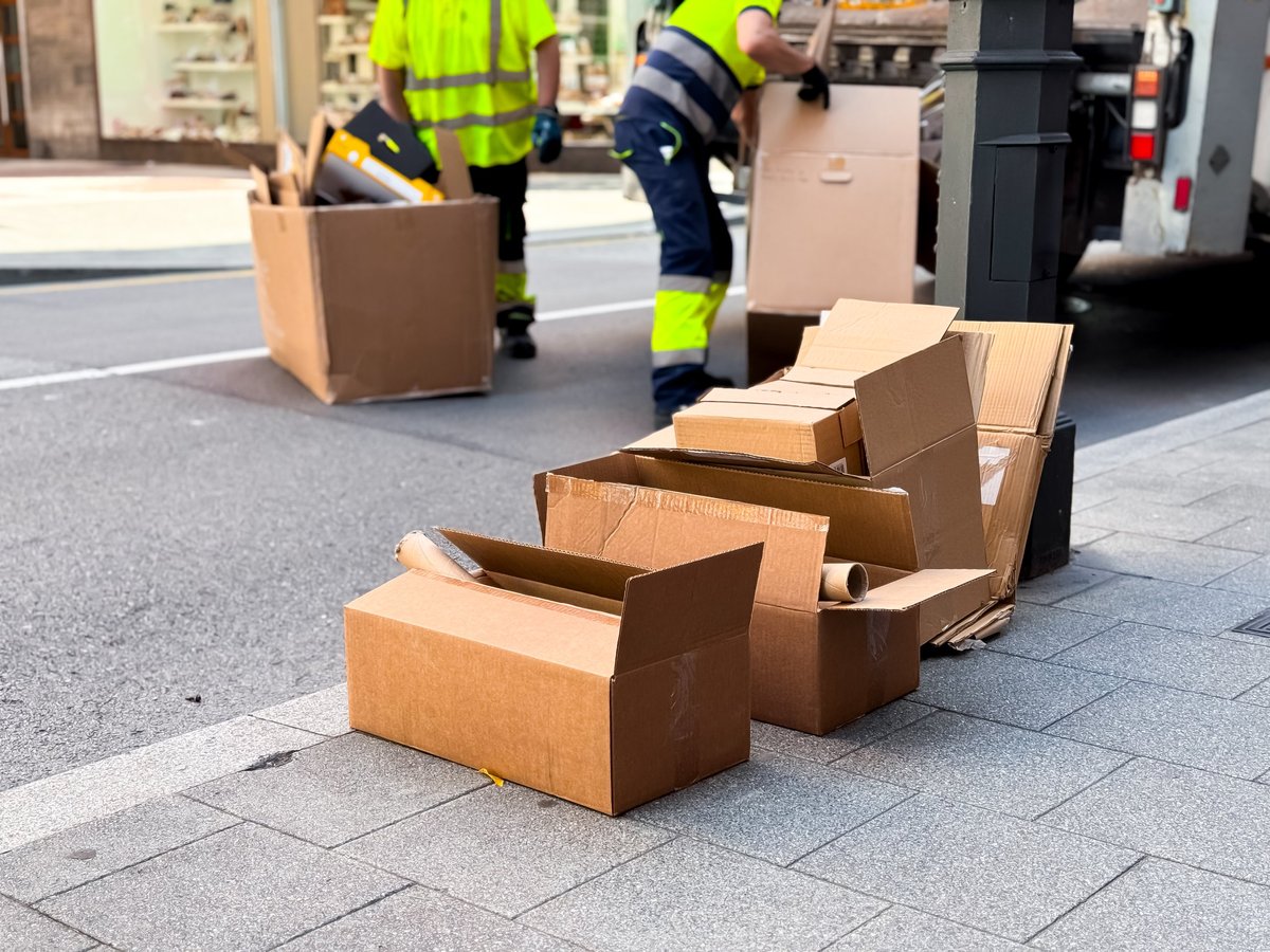 Workers loading cardboard boxes onto a city street sidewalk