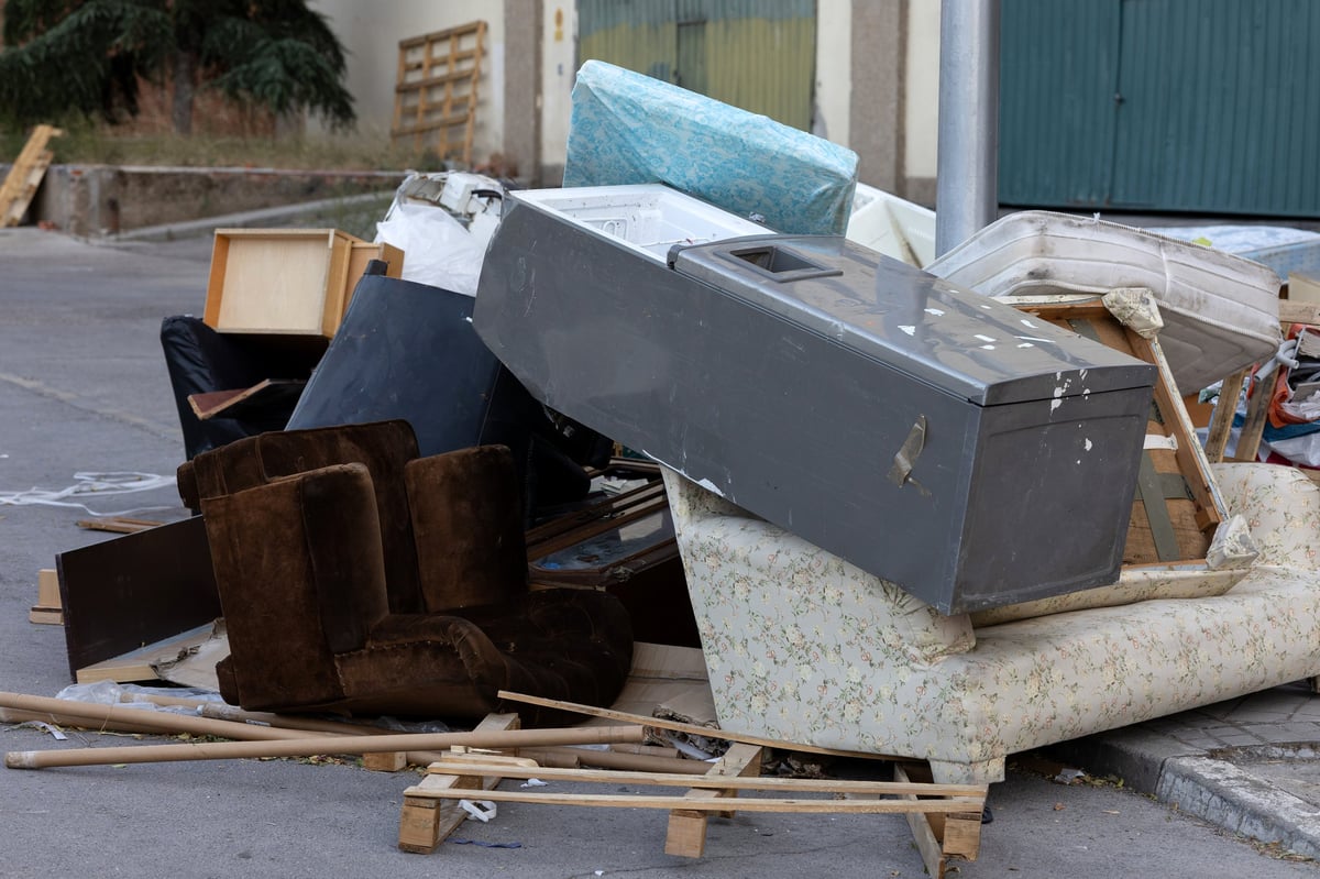 Bulky waste and old furniture piled on a city street pavement